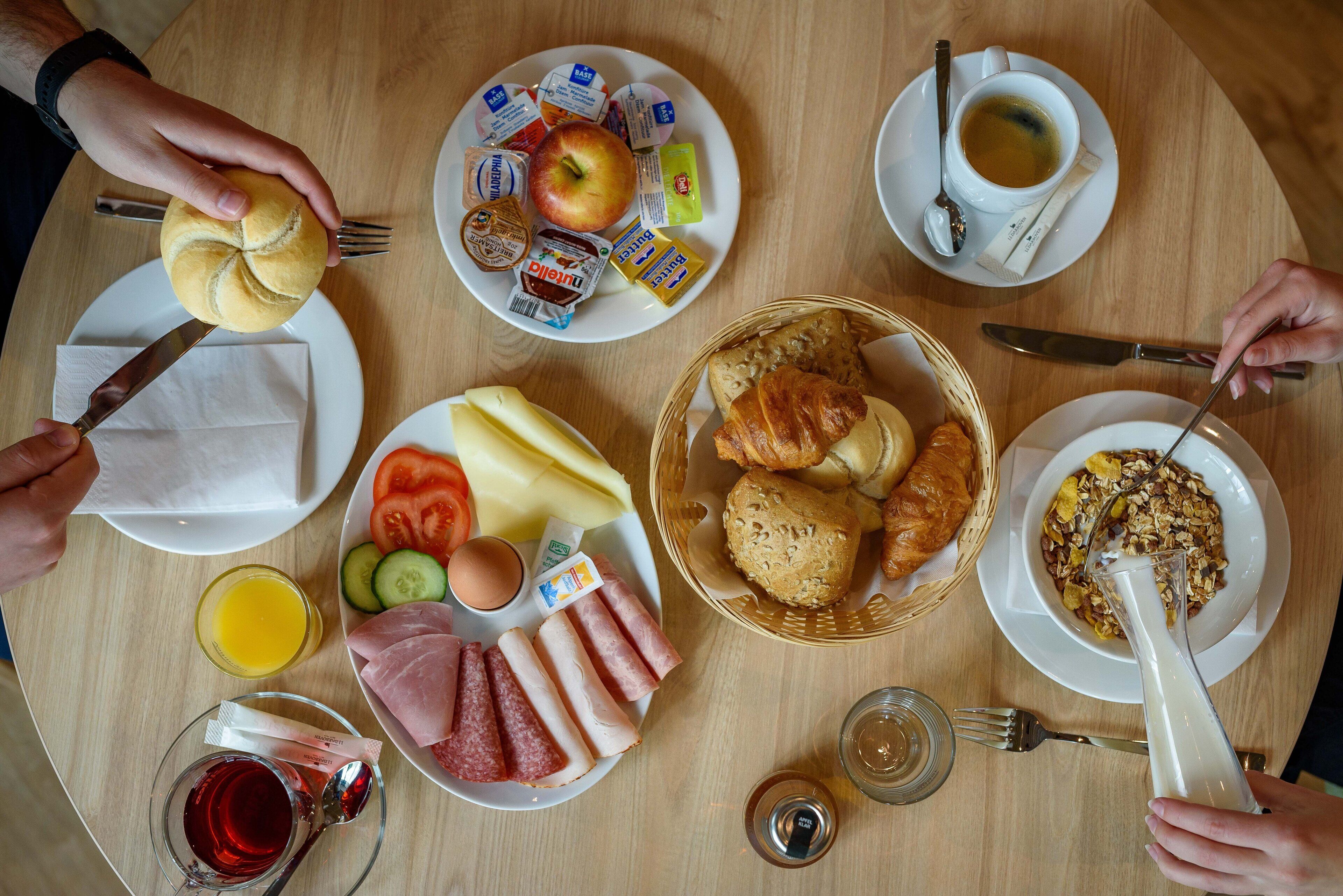 A breakfast table with various food items and utensils.