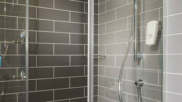 A modern shower with a glass door, a handheld showerhead, and a wall-mounted control panel.