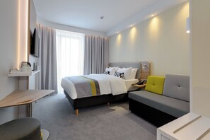 A modern hotel room with a bed, a sofa, a small table, and a TV. - Holiday Inn Express Fulda by IHG (Fulda)