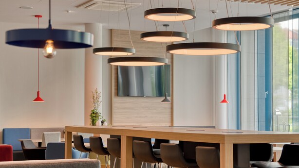 A modern conference room with a long wooden table, multiple chairs, and pendant lighting. - Holiday Inn Express Fulda by IHG (Fulda)