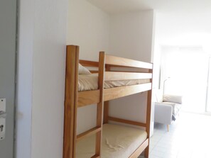 A bunk bed with a wooden frame and a lower bunk with a mattress.