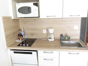 A compact kitchen with a microwave, coffee maker, and a dishwasher.