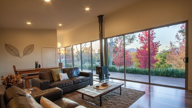 A modern living room with a large window, a fireplace, and a sofa.