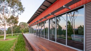 A modern building with a wooden deck, large windows, and a red exterior.