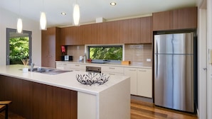 A modern kitchen with a large island, stainless steel appliances, and pendant lighting.