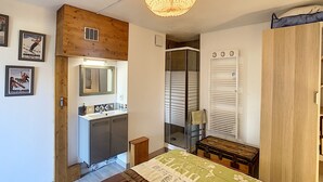A bedroom with a bed, a wooden wardrobe, a built-in wardrobe, a mirror, a sink, and a hanging light fixture. - Modern 2-Bedroom Apartment + Cabin, Close to Combloux Center (Combloux)