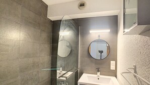 A modern bathroom with a glass-enclosed shower, a round mirror, and a white sink. - Modern 2-Bedroom Apartment + Cabin, Close to Combloux Center (Combloux)