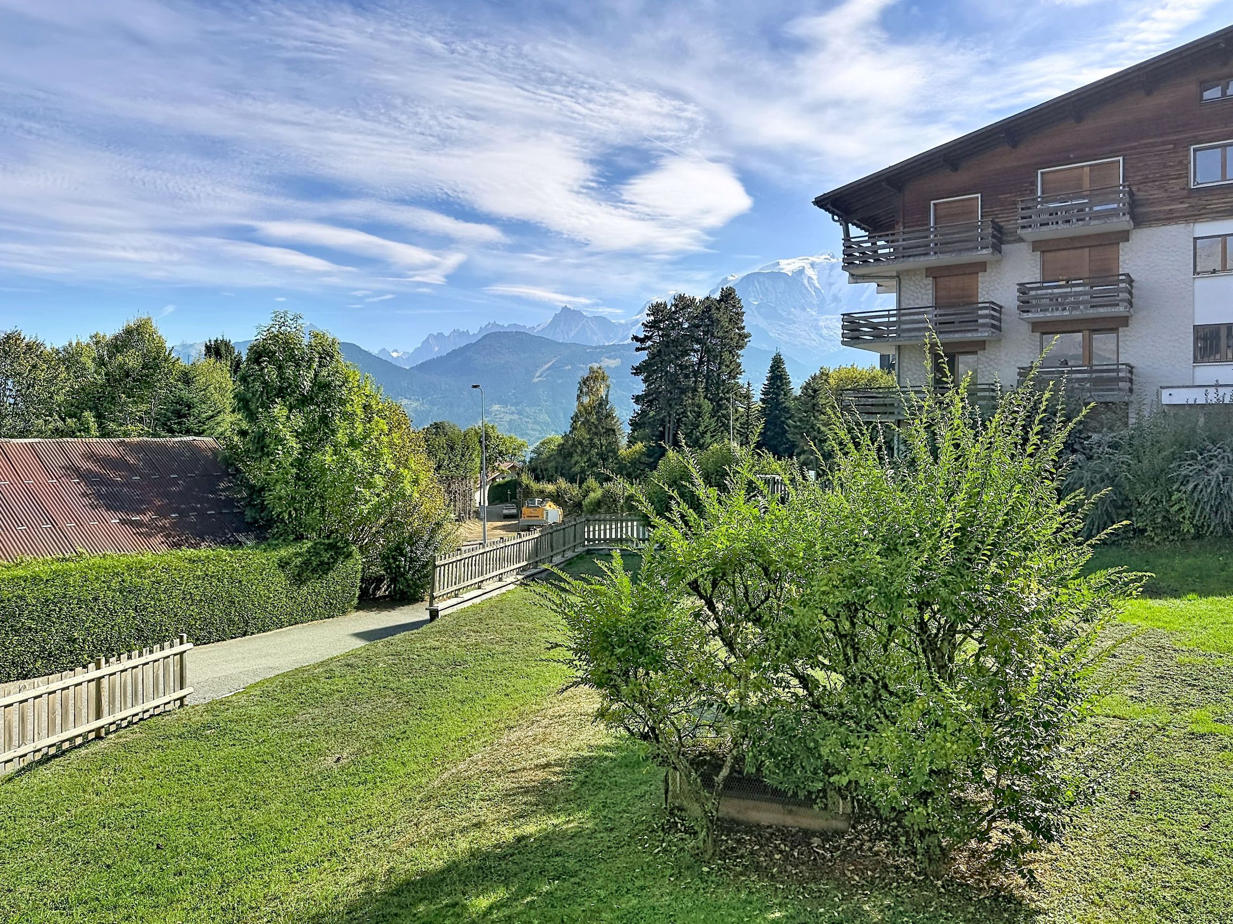 A residential area with a pathway leading to a building with balconies.