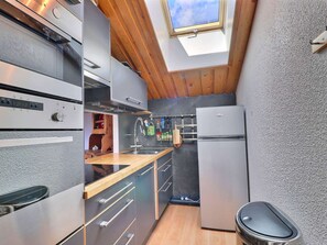A compact kitchen with a skylight, modern appliances, and wooden accents.