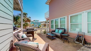 A covered outdoor patio with wicker furniture, a grill, and a hose reel. - Pet Friendly, 2 Shared Heated Pools, Parking for 3, Gated in Village Walk (Port Aransas)