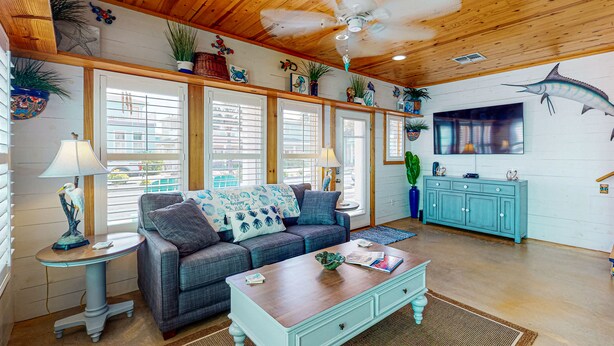 A cozy living room with a sofa, coffee table, and a TV mounted on the wall. - Pet Friendly, 2 Shared Heated Pools, Parking for 3, Gated in Village Walk (Port Aransas)