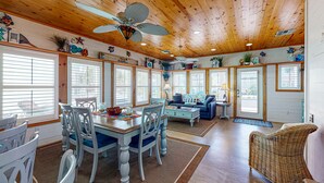 A spacious living area with a wooden ceiling, large windows, and a dining table with chairs. - Pet Friendly, 2 Shared Heated Pools, Parking for 3, Gated in Village Walk (Port Aransas)