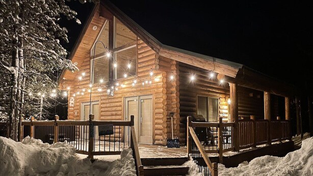 A log cabin with a wooden exterior, a covered porch, and steps leading up to the entrance.