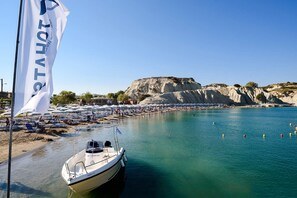 A boat docked near a beach with umbrellas and people.
