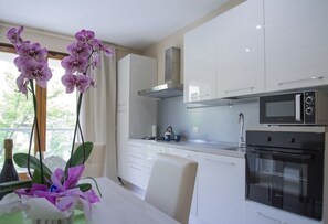 Een moderne keuken met witte kasten, een roestvrijstalen afzuigkap, een magnetron en een oven.