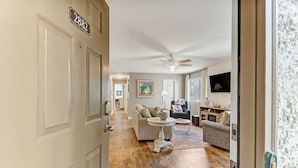A hallway leading to a living room with a ceiling fan, a dining area with a round table, and a sofa. - Pet Friendly | Updated Forest Ridge Villa | Short Walk to the Beach | Community Pool & Tennis (Fernandina Beach)