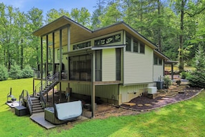 A modern house with a covered porch, a staircase, and a hot tub.