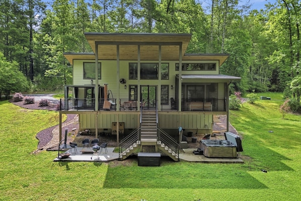A two-story house with a covered deck, a staircase, and outdoor seating.