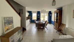 A spacious kitchen with a dining area, featuring a large window, a wooden cabinet, and a staircase.
