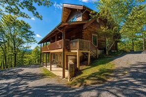 A wooden cabin with a porch, a covered deck, and a stone foundation. - Livin' Lodge, Hot Tub, WIFI, $560 FREE tickets each paid day, Pool Table, WIFI! (Sevierville)