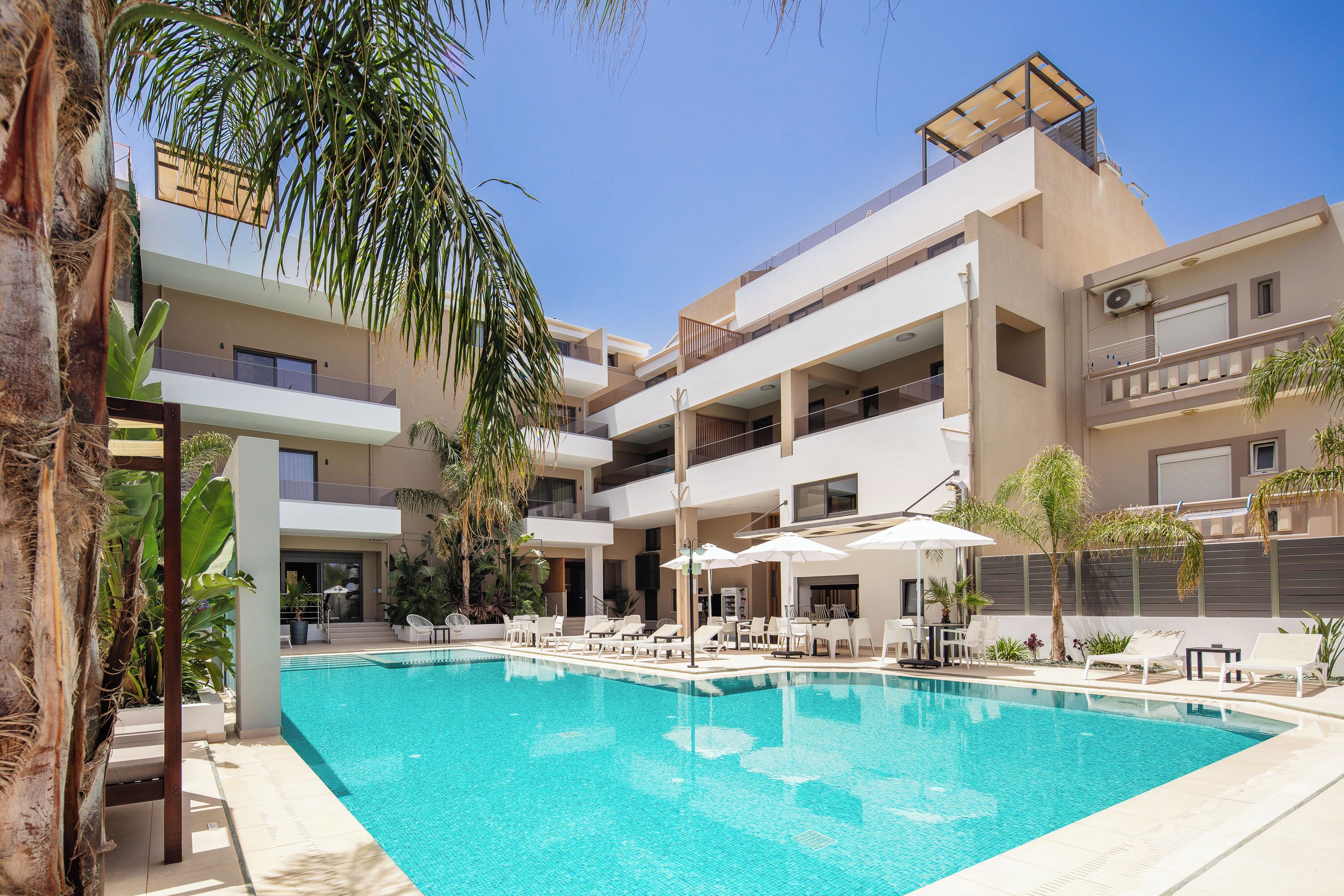 Ein modernes Hotel mit Schwimmbad, mehreren Balkonen und Sitzbereichen im Freien.