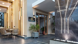 A modern hotel entrance with a reception desk, seating area, and a large sign for 'Sapphire Suites'. - Sapphire Blue Suites (Kissamos)