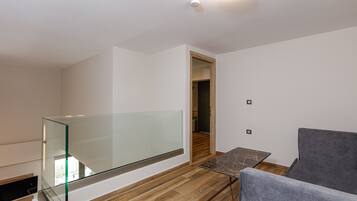 A modern interior with a glass balcony, a dining area with a table and chairs, and a wooden floor.