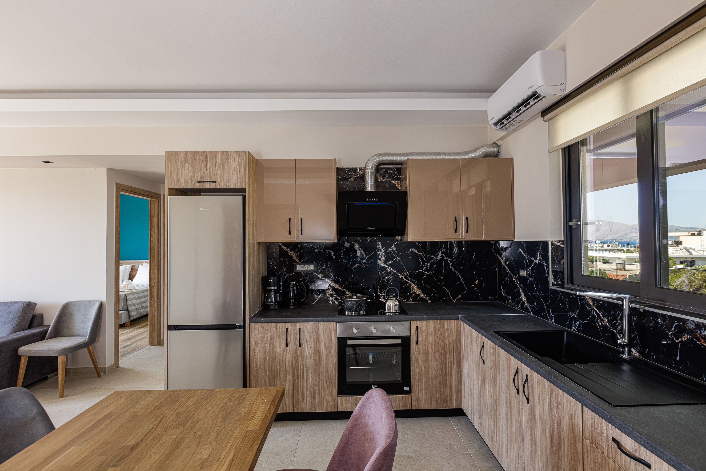 Une cuisine moderne avec des meubles en bois, un plan de travail noir et un four encastré.