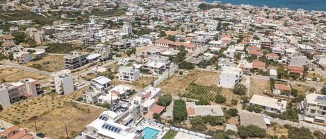 An aerial view of a coastal residential area with buildings, a swimming pool, and a beach.