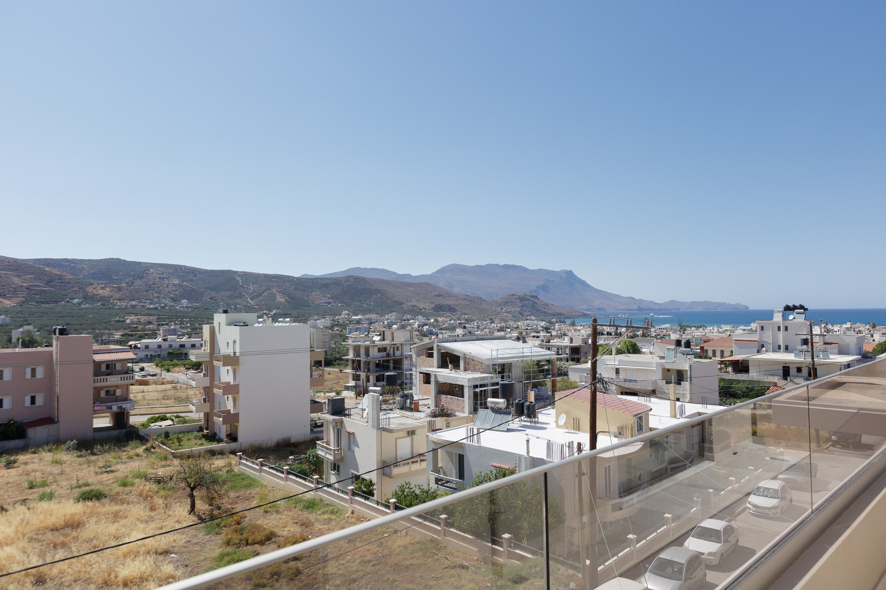 A residential area with modern buildings, a clear sky, and a distant mountain range.