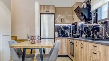 A modern kitchen with a marble countertop, wooden cabinets, and a pendant light.