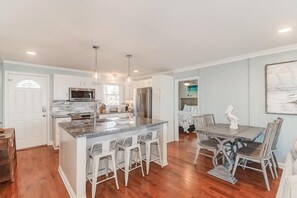 A modern kitchen with granite countertops, white cabinetry, and a central island with bar stools.