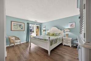 A bedroom with a bed, a chair, a nightstand, and a dresser.