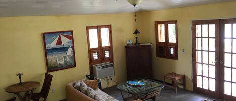 A room with a ceiling fan, a sofa, a small table, a cabinet, and a door with windows.