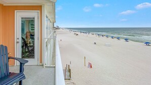 Blick auf den Strand vom Balkon mit Stuhl und Tür.