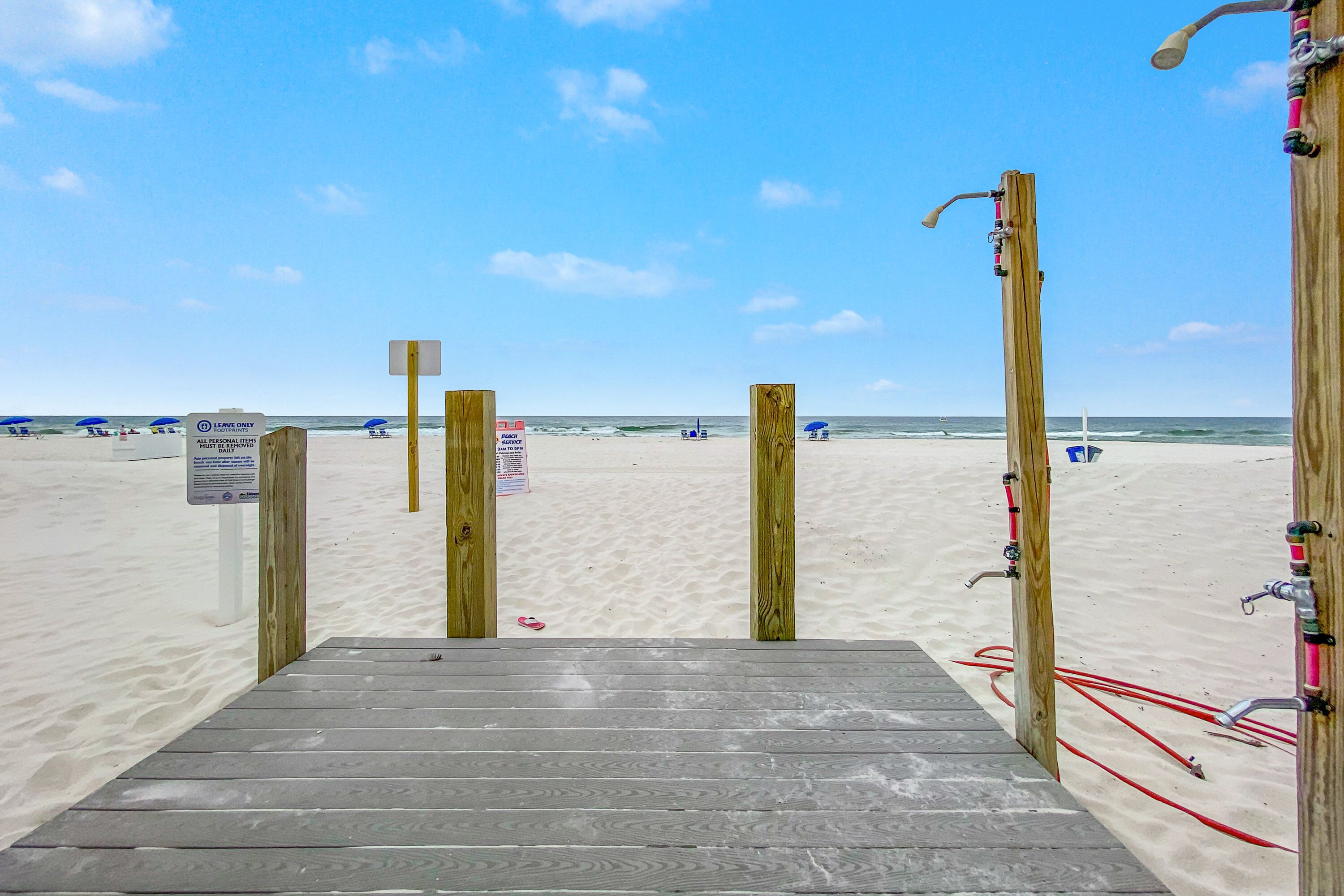 A wooden staircase leading to a beach with clear skies.