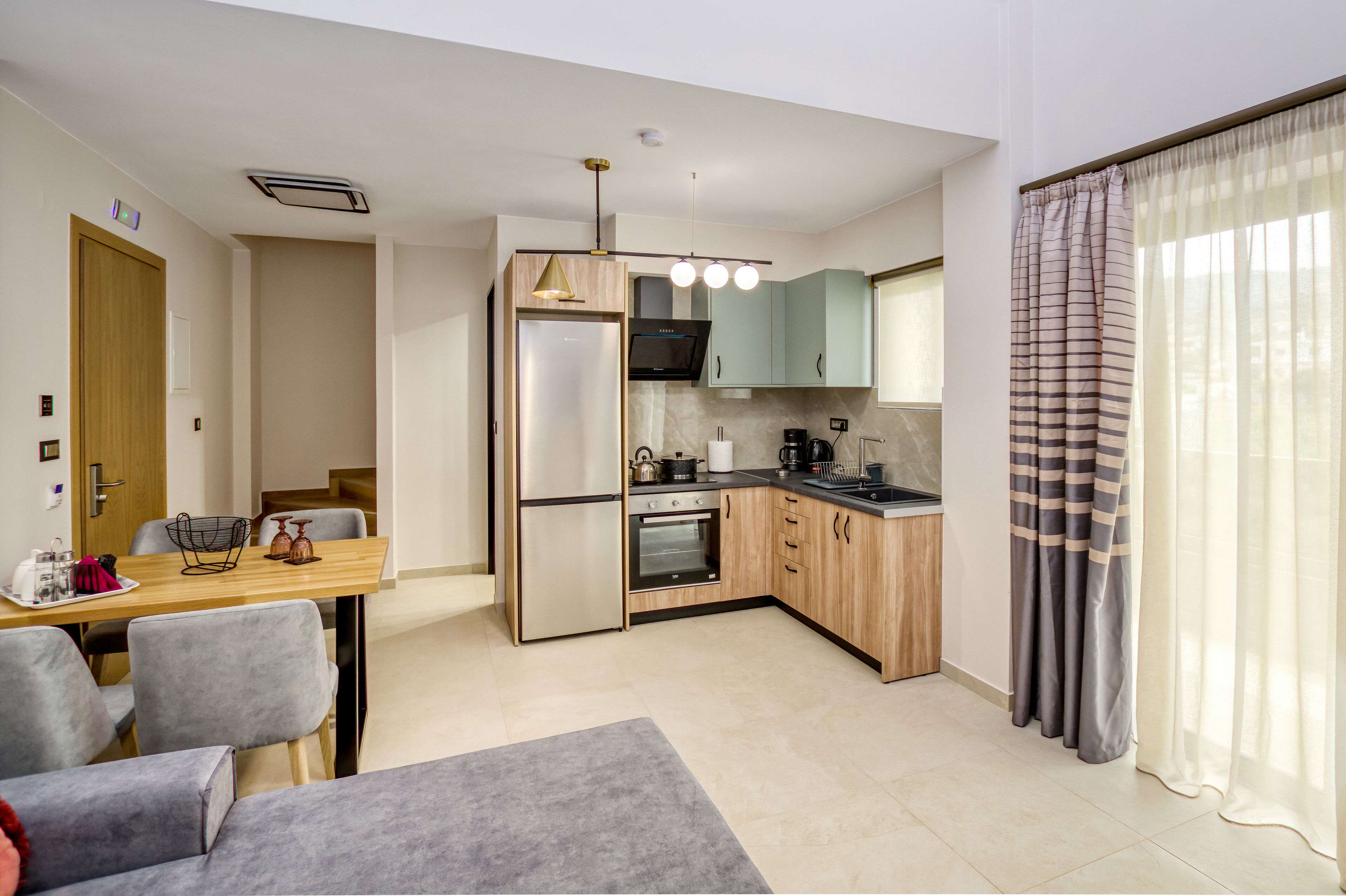 A modern kitchen with a dining area, wooden cabinets, a built-in oven, and a dining table with chairs.