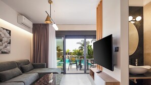A modern living room with a grey sofa, a marble coffee table, a flat-screen TV, and a large window overlooking a pool area. - Sapphire Horizon Suites (Kissamos)