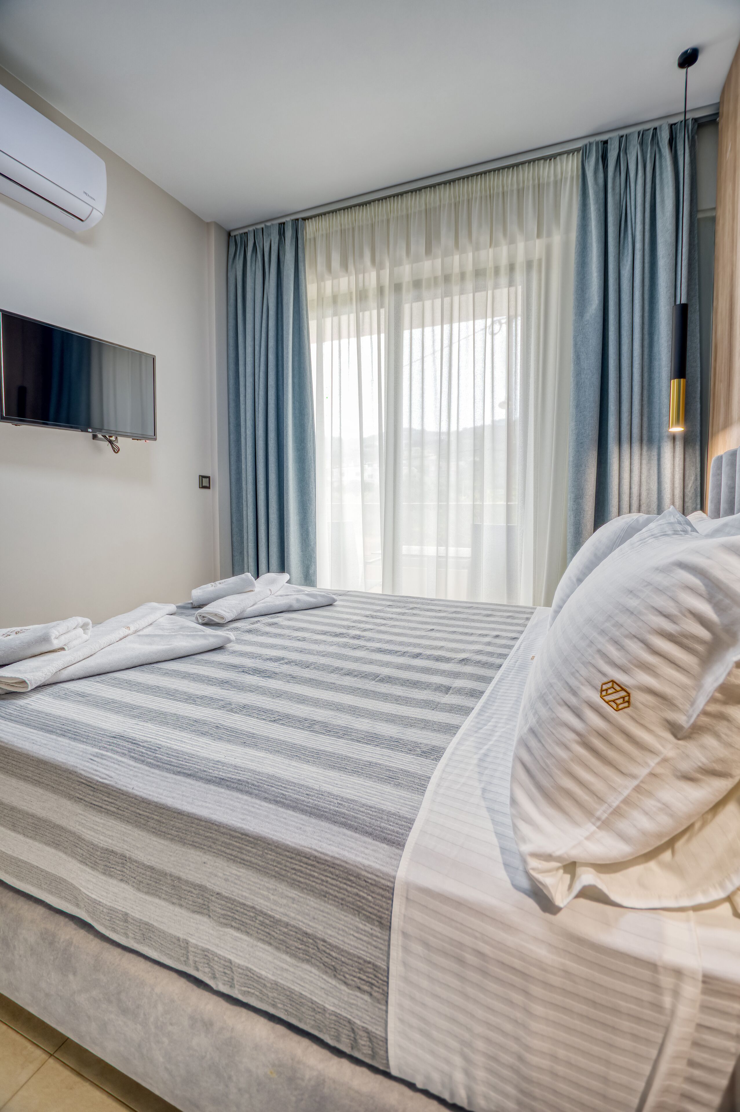 Een hotelkamer met een bed, een flatscreen-televisie en een raam met gordijnen.