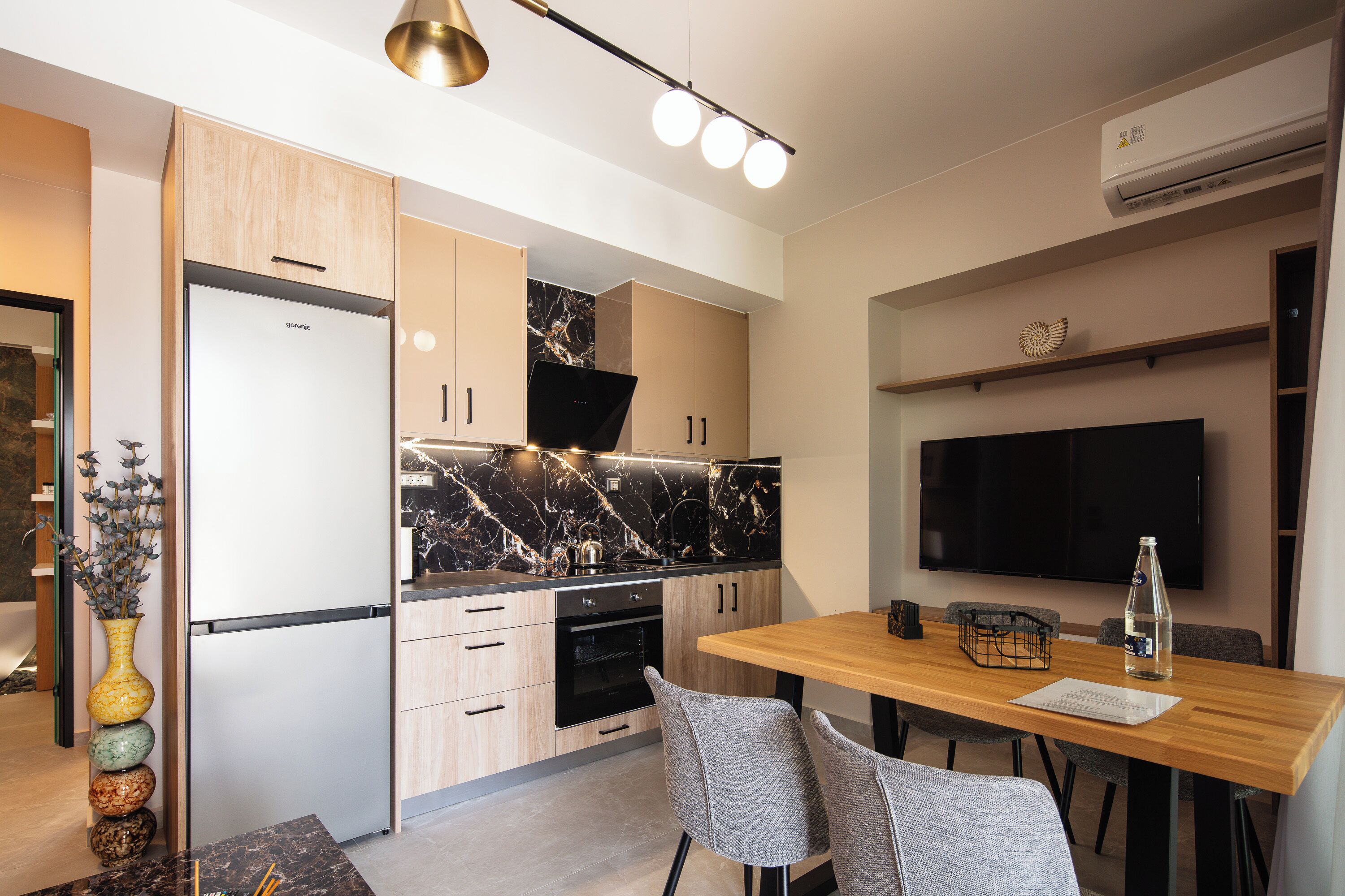 Een moderne keuken met een marmeren spatwand, een inbouwoven en een eethoek met een houten tafel en stoelen.