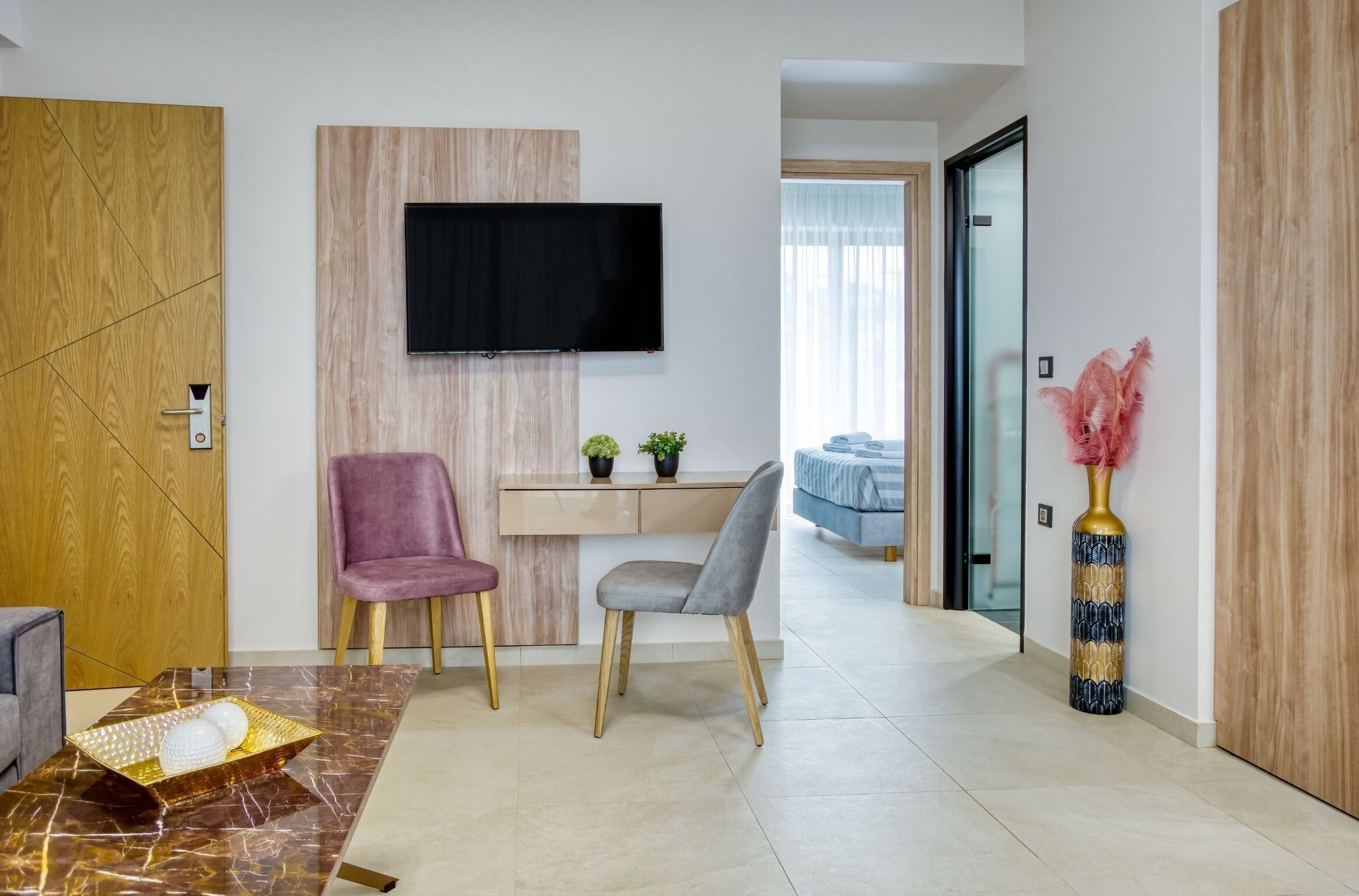 Una sala de estar moderna con un televisor de pantalla plana, dos sillones, una mesa de centro y un jarrón decorativo.