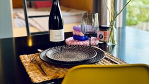 A dining table with a bottle of Burleith wine, a glass, a woven placemat, and a decorative vase with flowers.