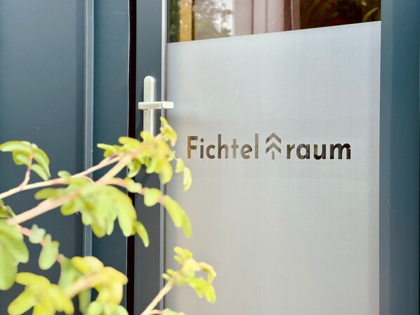 Une porte sur laquelle est apposée une plaque portant l’inscription « Fichtelraum », avec une petite plante placée en avant.
