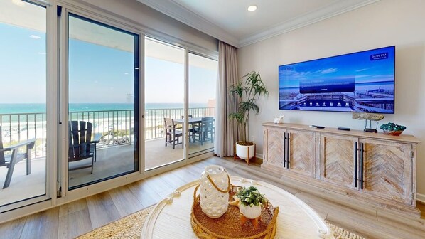 Una habitación de hotel con balcón, televisión, planta y bandeja decorativa.