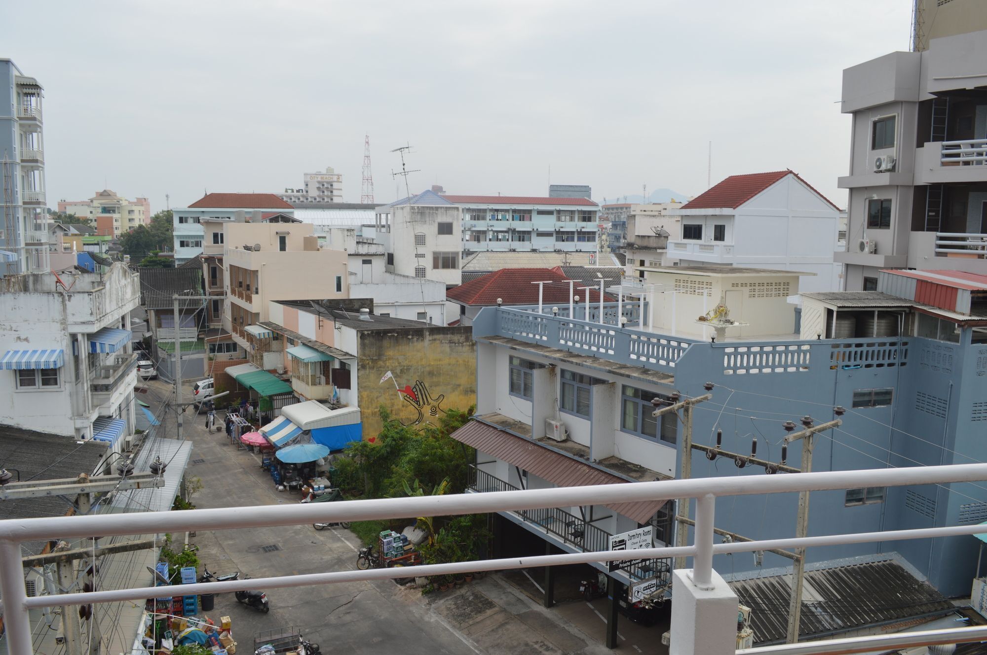 A cityscape with buildings, a street, and a blue fence.