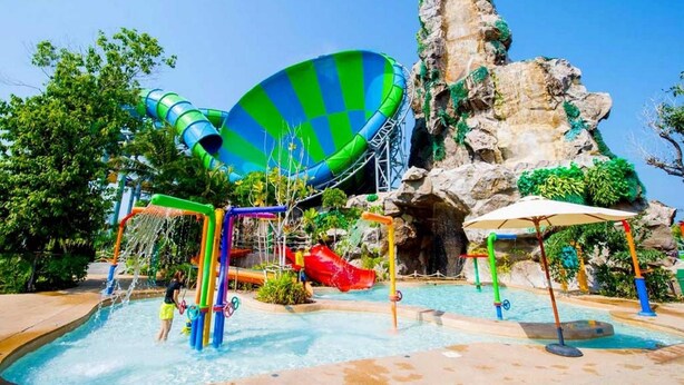 Un parc aquatique doté d’un grand toboggan aquatique, d’une piscine et d’un décor rocheux.