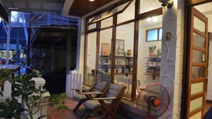 Une pièce confortable avec une grande fenêtre, un ventilateur et une bibliothèque remplie de livres.