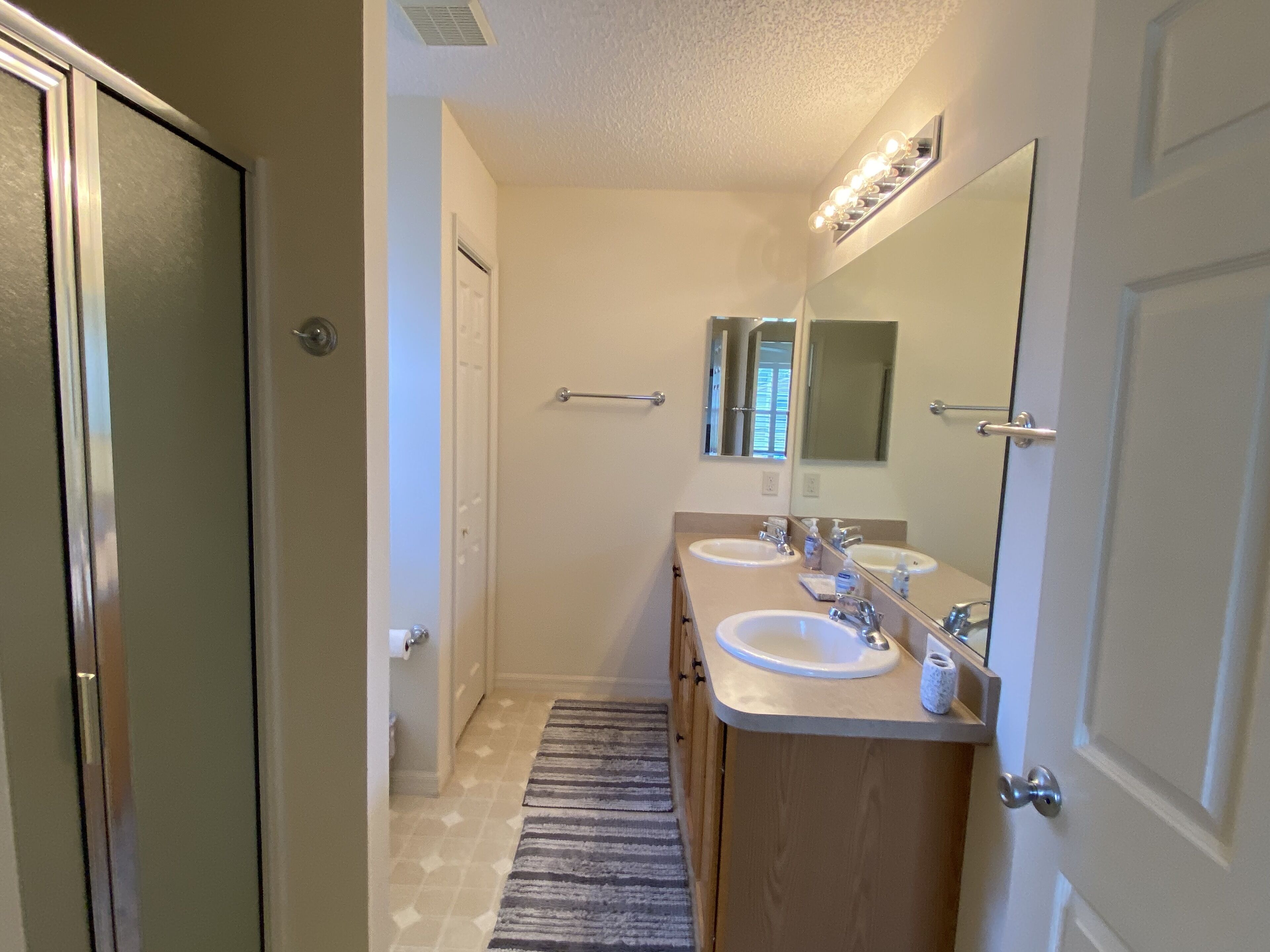 A modern bathroom with two sinks, a mirror, and a shower.