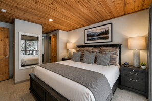 A bedroom with a wooden ceiling, a bed with patterned pillows, a bedside lamp, and a framed picture on the wall. - 51 Snowflower 2 Bedroom Condo by RedAwning (Park City)