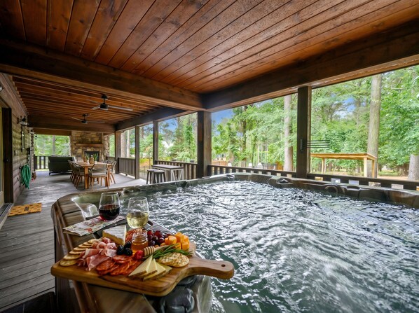 Un jacuzzi con muelle de madera, rodeado de un deck de madera y amplios ventanales.